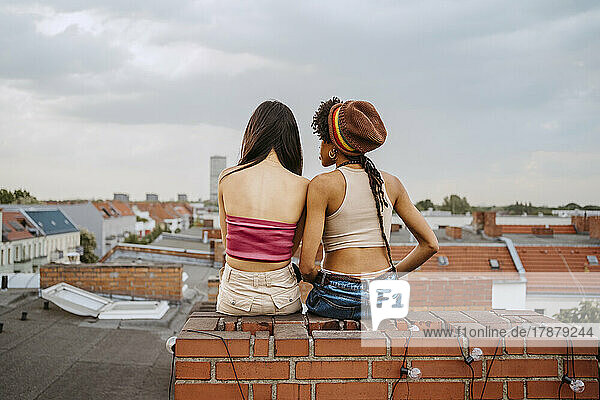 Rear view of young women sitting together on rooftop