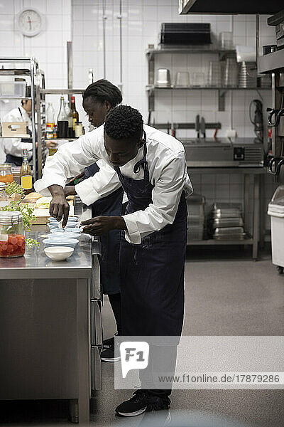 Männliche und weibliche Köche arbeiten an der Küchentheke eines Restaurants