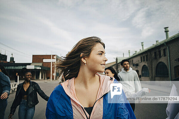 Young woman with friends walking on street in city
