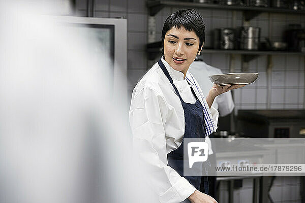 Chef with short hair carrying plate while working at restaurant kitchen