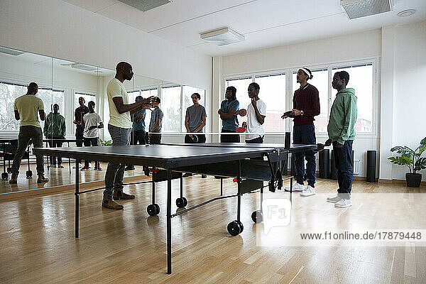 Coach giving table tennis instructions to students in games room