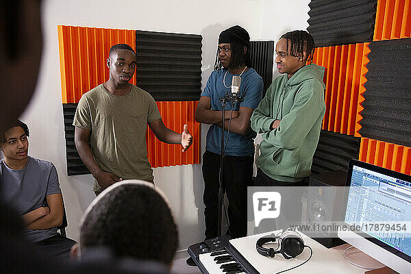 Sound engineer and rappers discussing in recording studio
