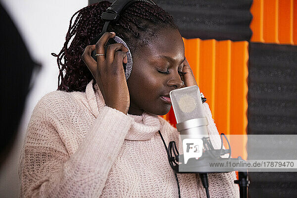 Konzentrierter Sänger mit geschlossenen Augen bei der Aufnahme eines Songs im Studio