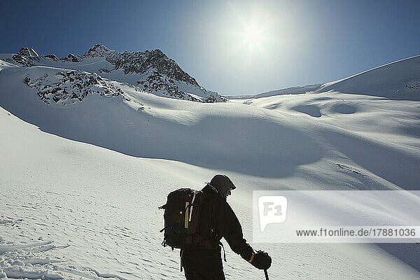 Male skier with backpack on sunny  snowy mountain slope  Selkirk Mountains  Canada