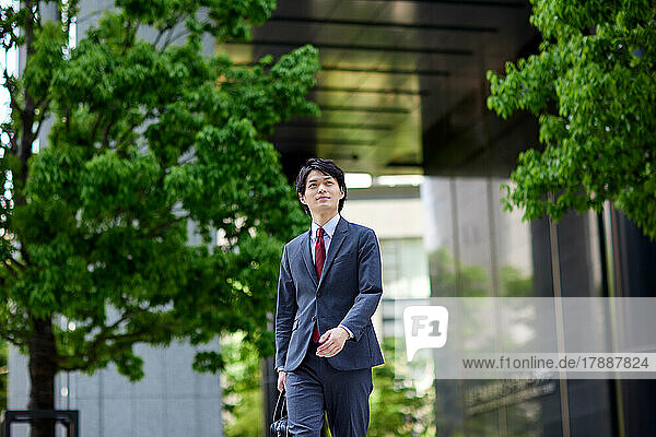 Japanischer Geschäftsmann beim Spaziergang im Geschäftsviertel