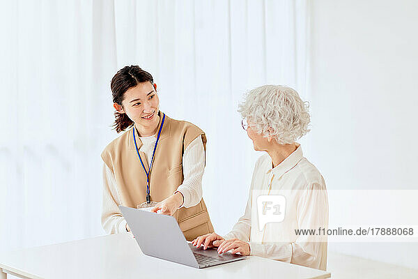 Japanische Seniorin lernt zu Hause den Umgang mit dem Laptop