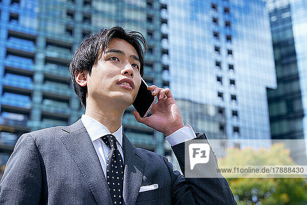 Japanischer Geschäftsmann am Telefon im Geschäftsviertel