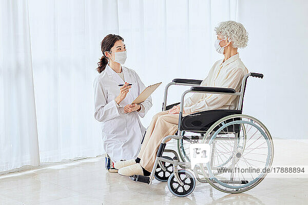 Japanische Seniorin im Rollstuhl und Krankenschwester