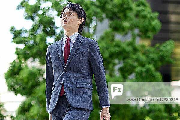 Japanischer Geschäftsmann beim Spaziergang im Geschäftsviertel