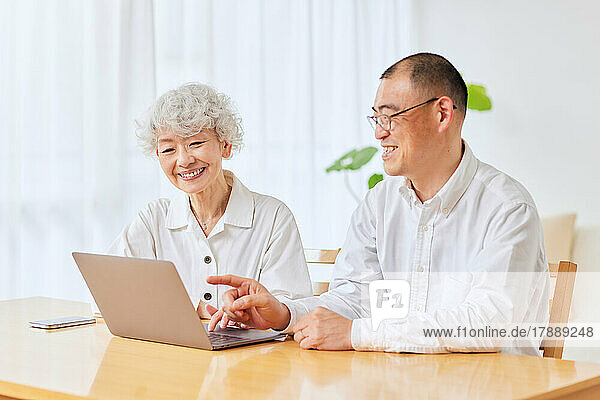 Japanische Seniorin lernt zu Hause den Umgang mit dem Laptop