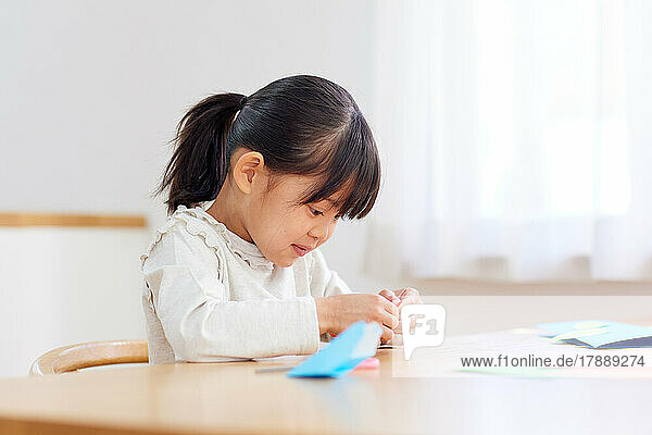 Japanese kid playing with origami at home