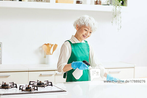 Japanische Seniorin beim Putzen der Küche