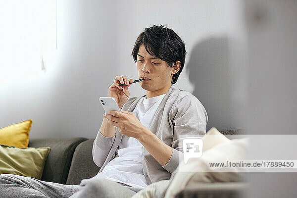 Japanese man brushing teeth on the sofa