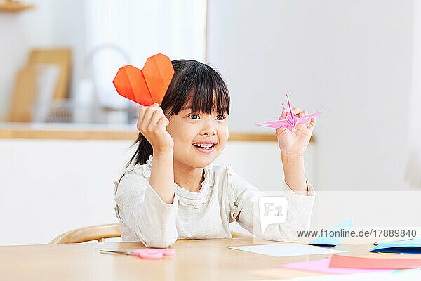 Japanisches Kind  das zu Hause mit Origami spielt