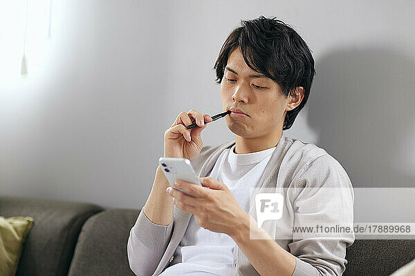 Japanischer Mann beim Zähneputzen auf dem Sofa