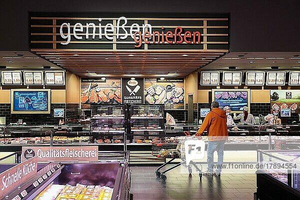 Man in orange jacket and shopping trolley standing in front of the service counter for cheese  meat and sausage products  Famila Nordost Warenhaus  22926 Ahrensburg  Schleswig-Holstein  Germany  Europe
