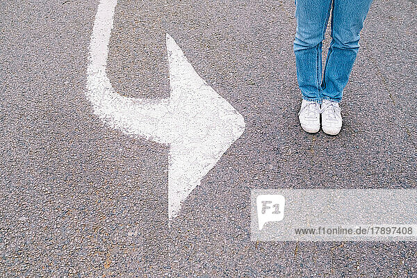 Woman standing by arrow symbol on road