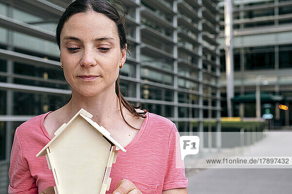 Woman with house model by building