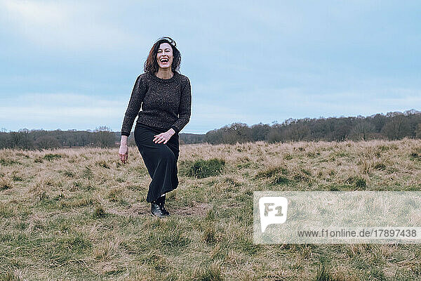 Cheerful mature woman walking at field