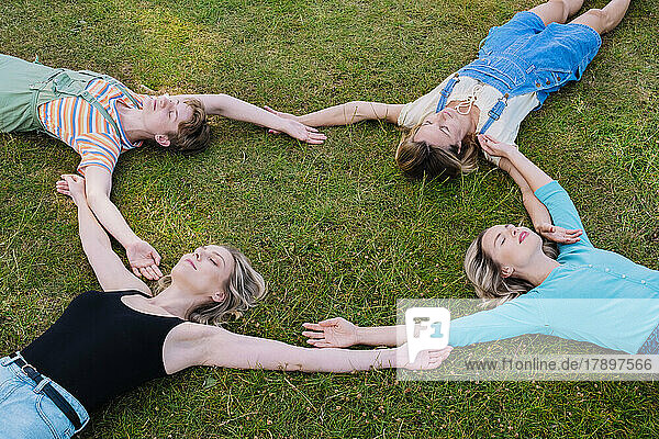 Friends with eyes closed lying together on grass at park
