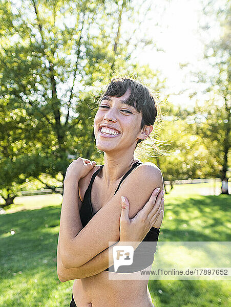 Happy young athlete hugging self in park