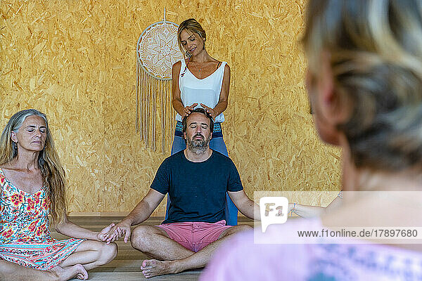 Yoga instructor teaching meditation to friends sitting on floor