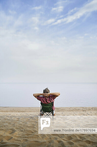 Man relaxing sitting on folding chair at beach