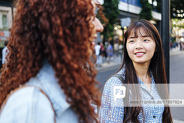 Smiling woman with friend walking on street