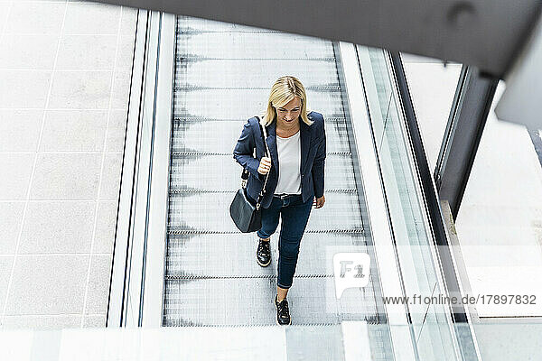 Blond businesswoman walking on moving walkway