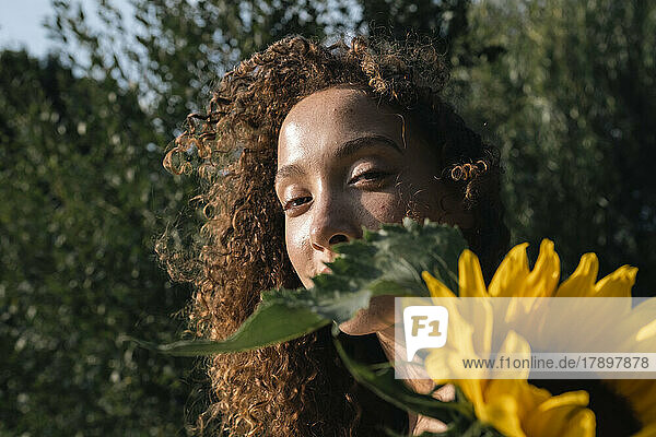Young woman with sunflower on sunny day