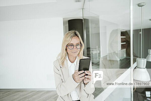 Businesswoman with glasses using mobile phone in office