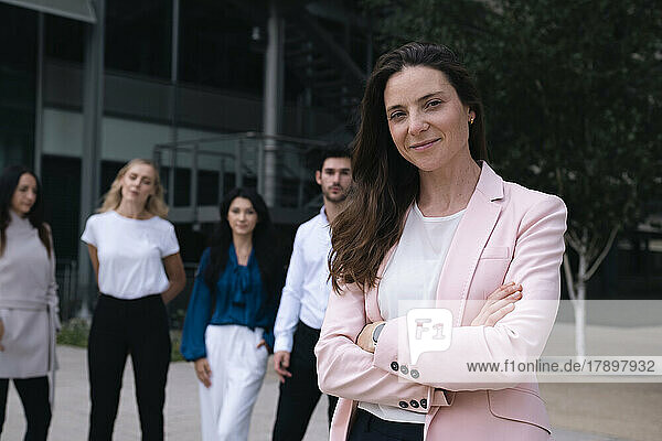 Smiling businesswoman standing with arms crossed in office park
