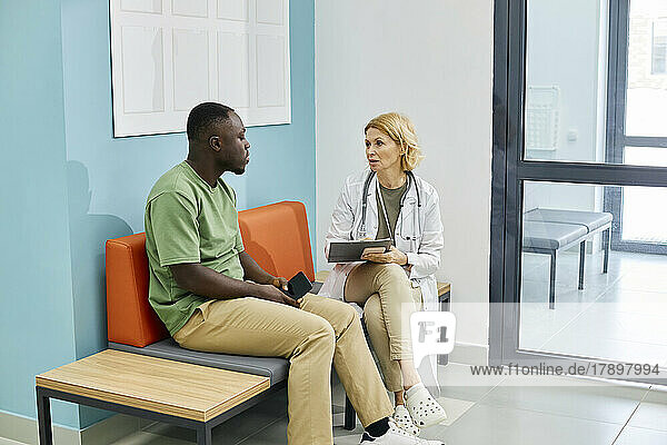 Doctor discussing with patient sitting on couch in clinic