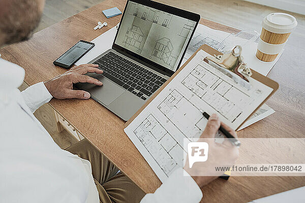 Architect with blueprint working at desk