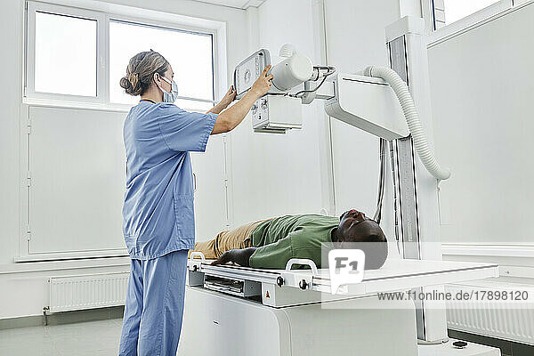 Nurse adjusting X-ray machine for patient in clinic