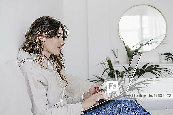 Young woman with card credit shopping online through laptop