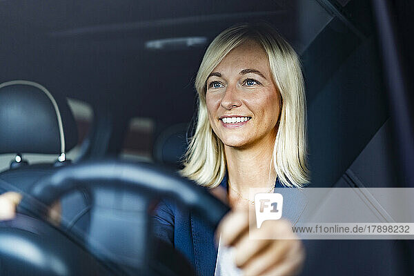 Smiling businesswoman driving car seen through windshield