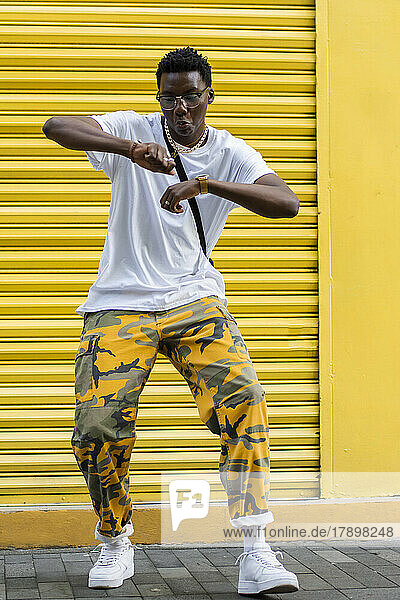 Man dancing in front of yellow shutter