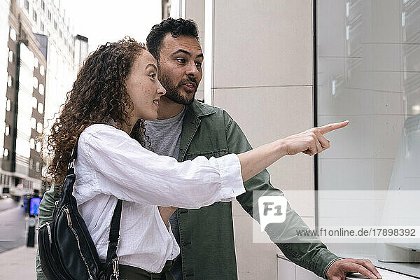Man talking to woman pointing at store window