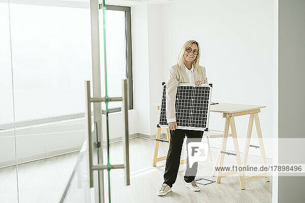 Woman holding solar panel in office
