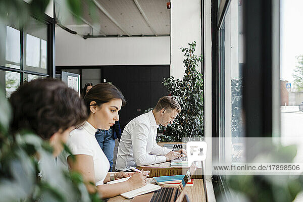Geschäftsleute arbeiten im modernen Büro mit Laptop zusammen