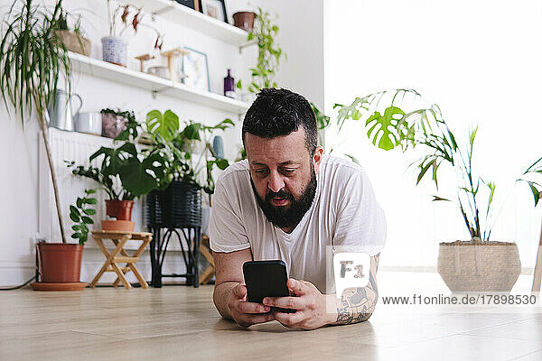 Man using smart phone lying at home