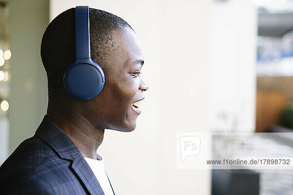 Glücklicher junger Mann mit kabellosen Kopfhörern  der Musik hört