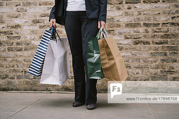 Woman standing with shopping bags at footpath