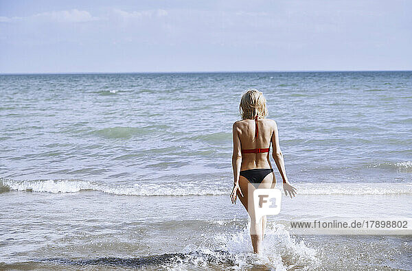 Woman in bikini walking at beach on sunny day