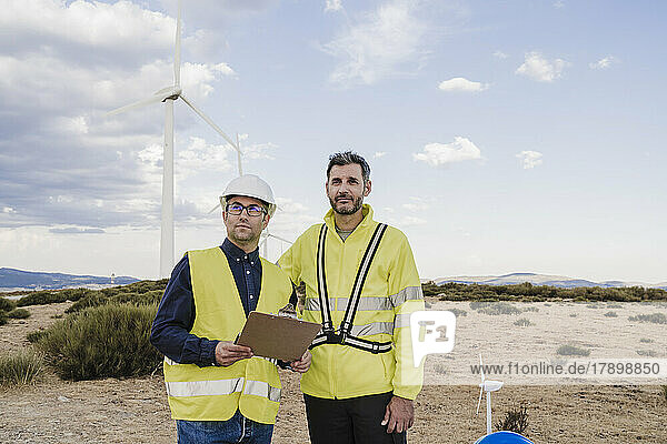 Engineers wearing reflective clothing standing at wind farm