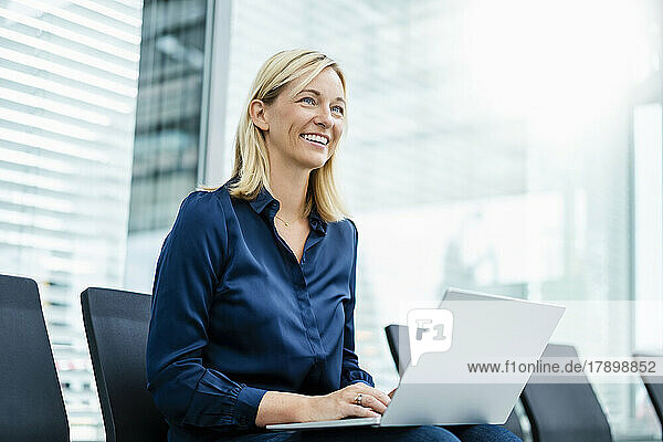Contemplative businesswoman with laptop sitting on chair