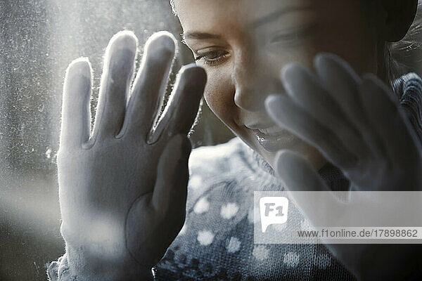 Smiling woman looking through frost window