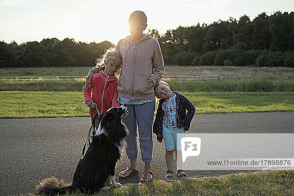 Mutter mit Töchtern und Hund stehen zusammen