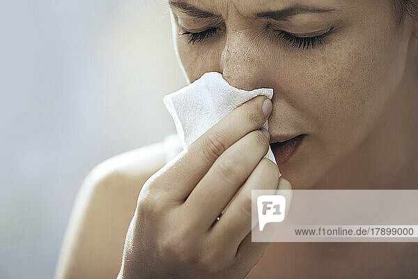 Ill woman blowing nose with tissue paper